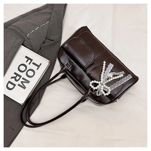 Close-up of chocolate brown patent leather tote with lace pearl bow detail and long handles