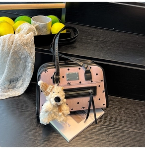 Detail of pink polka dot canvas tote bag with black zipper pocket and plush bear charm
