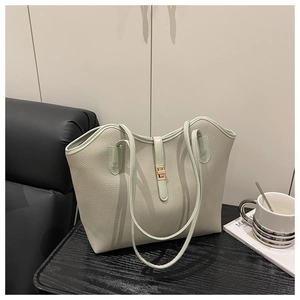 Detail of light green pebble leather tote bag with elegant golden twist lock on a table