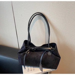 Detail shot of black suede tote bag with slim shoulder straps and metallic buckle closure