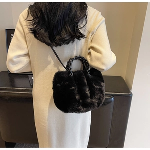 Close-up of fluffy black faux fur bag with a chunky woven handle on a white knit dress