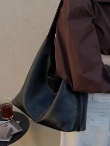 Retro black large capacity soft leather tote bag worn by model in minimalist studio