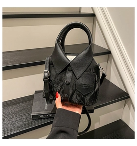 Detail of creative black shirt-shaped bucket bag featuring collar and button accents