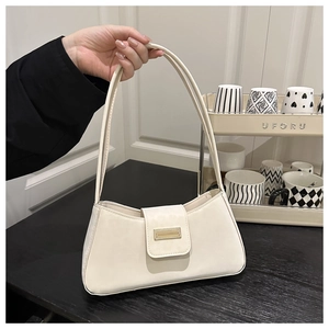 Détail du sac baguette en cuir crème minimaliste avec un fermoir métallique doré chic