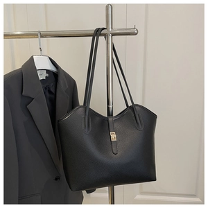 Close-up of black lychee grain leather tote bag with elegant gold metal lock detail