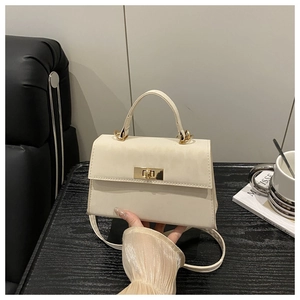 Nahaufnahme der cremeweißen Handtasche mit eleganter goldfarbener Drehschnalle aus Kunstleder