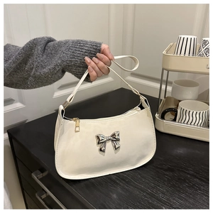 Détail du sac sous le bras en PU blanc avec nœud en métal argenté et zip doré brillant