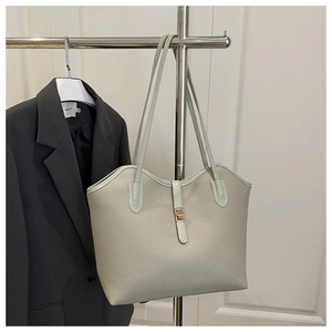 Detail of sage green tote bag featuring lychee texture and gold turn-lock closure