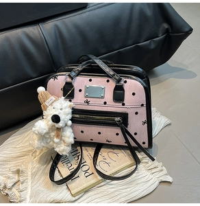 Close-up of pink polka dot tote bag with cute bear charm and silver metal logo plate