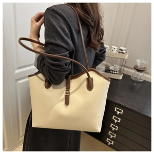 Detailed side view of a large capacity two-tone tote bag with lychee texture and silver hardware