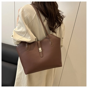 Detail of dark brown tote bag featuring litchi texture and golden buckle on model
