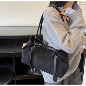 Detail of black matte suede tote bag with slim leather straps worn on shoulder