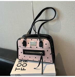 Detail of pink canvas tote with black polka dots, bow embroidery, and silver metal plaque
