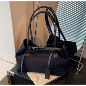 Detail of black suede tote bag with slim leather straps and elegant metal buckle accent