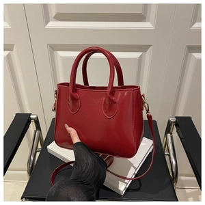 Detail of red patent leather tote bag with glossy finish and gold metal hardware