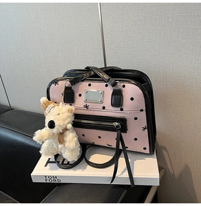 Pink canvas handbag with black polka dots and a cute plush bear charm on a Tom Ford book