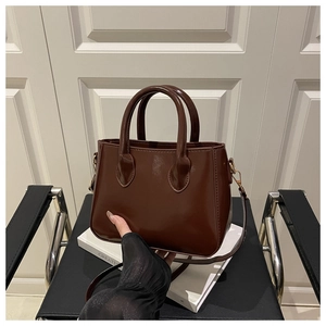 Detail of caramel glossy patent leather handbag with gold metal hardware and top handle