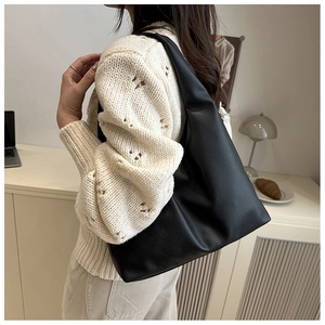 Detail view of large black leather shoulder bag showing pebbled texture and half-moon shape
