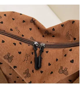 Detail of smooth double metal zipper on a brown corduroy bag with heart and bow patterns