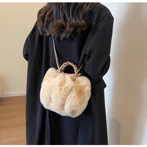 Detail of plush beige crossbody bag with woven handle on a black winter coat