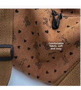 Detail view of brown corduroy fabric with black heart prints and woven shoulder strap