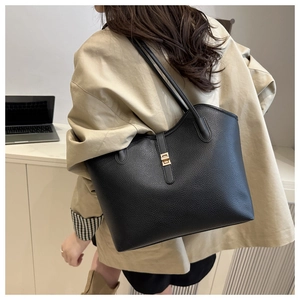 Detail of black pebbled leather tote bag with wavy edge and gold twist lock closure