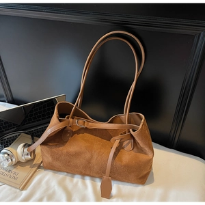 Close-up of brown suede tote bag featuring fine metallic buckle and leather strap detail