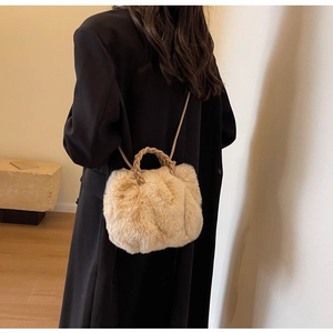 Detail of soft plush faux fur handbag with woven handle and shoulder strap worn with coat