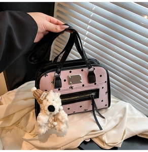 Detail of pink polka dot handbag with bow patterns and a plush teddy bear charm