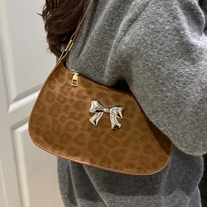 Sac sous le bras imprimé léopard avec nœud papillon argenté porté par un mannequin