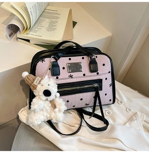 Detail of pink polka dot canvas tote with black leather trim and cute bear charm
