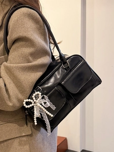 Glossy black tote bag with pearl bow and lace charm pendant shown on a model