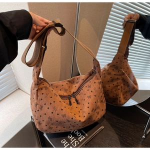Close-up of brown corduroy crossbody bag with heart patterns and dual zipper detail
