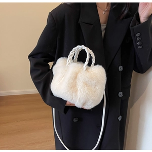 Detail showing the plush faux fur texture and woven handles of a cream winter handbag