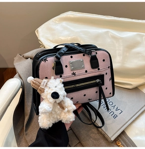Detail of pink polka dot handbag with leather trim and cute plush bear charm accessory