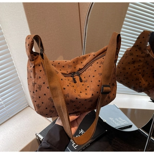 Detail of brown corduroy crossbody bag featuring heart and bow patterns with adjustable strap