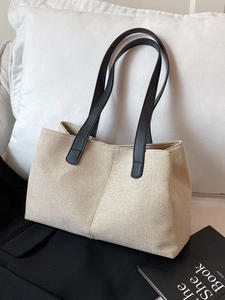 Minimalist beige woven canvas tote bag with black leather straps in a lifestyle setting