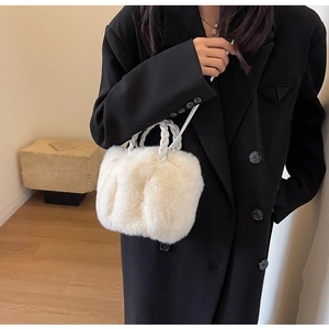 Detail of soft cream plush handbag with woven handle texture shown on a black blazer