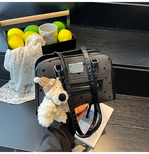 Detail of black polka dot denim tote with silver metal plaque and plush bear charm