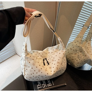 Close-up of cream corduroy dumpling bag with heart and bow patterns and double zippers