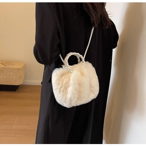 Détail d'un sac en peluche crème avec une poignée tissée et une fine bandoulière