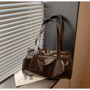 Detail of dark brown glossy patent leather texture and metal zipper on baguette bag