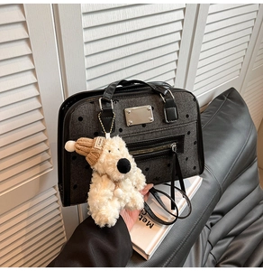 Detail of grey polka dot tote bag with a plush dog charm and black leather trim accents