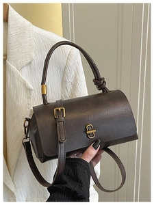 Detail of vintage textured leather handbag with gold metal clasp on a stylish white blazer
