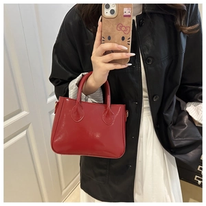 Close-up of a glossy red patent leather handbag with a high-shine finish and dual handles