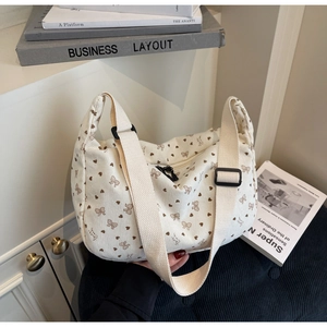 Close-up of cream corduroy crossbody bag with brown heart and bow floral patterns