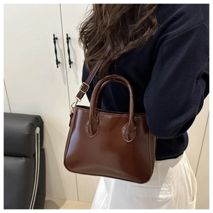 Detail view of brown patent leather mini tote bag with adjustable shoulder strap