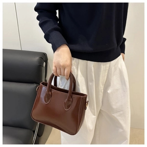 Close-up of the smooth brown leather finish and metal buckles on this mini tote handbag