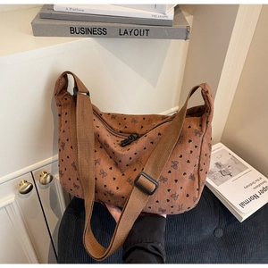 Detailed texture of brown corduroy hobo bag with heart and bow patterns and wide strap