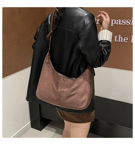 Detail of a brown suede hobo bag with a minimalist crescent design and smooth metal zipper